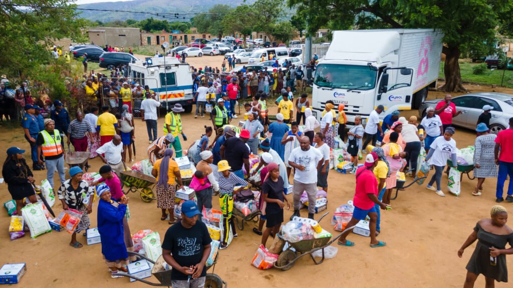 People collecting grocery parcels next to a MySol-branded truck at a community distribution